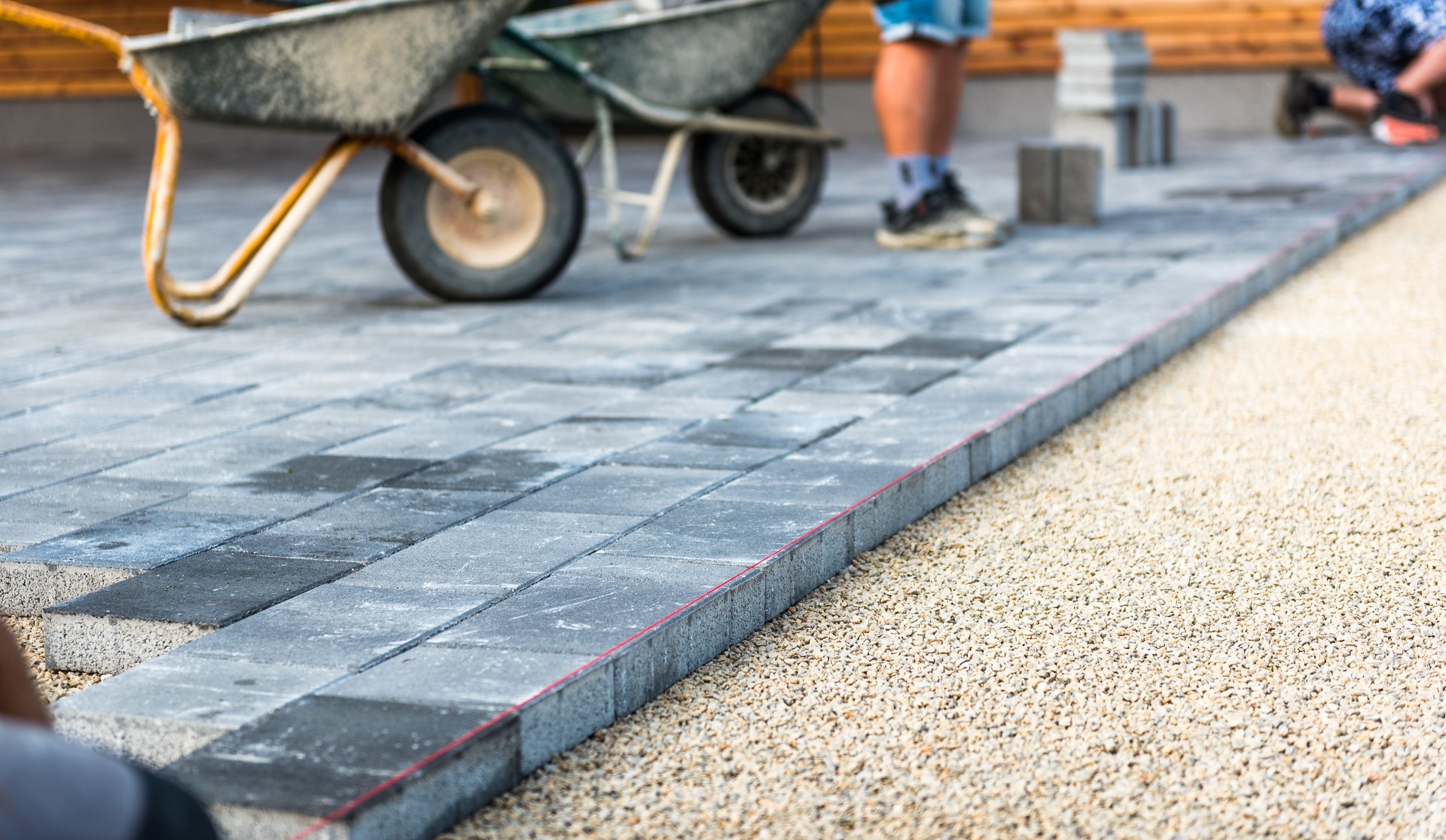 Laying gray concrete paving slabs in house courtyard driveway patio.