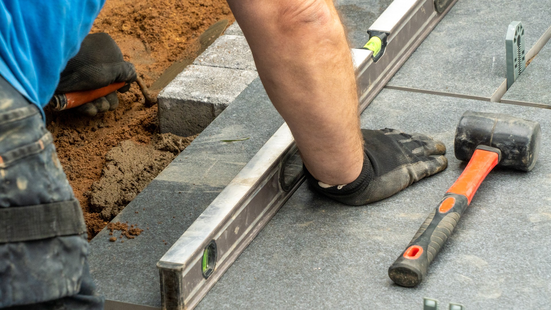 Expert workman laying patio edging bricks in garden makeover